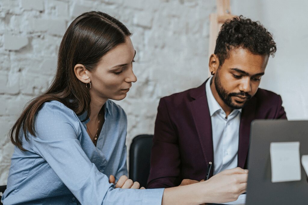 Image of two people at work looking over laptop information